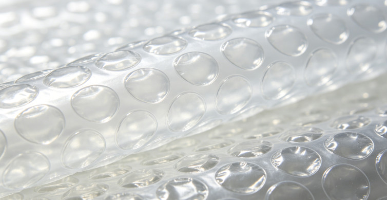 Close-up view of clear bubble wrap with raised air filled bubbles, folded into overlapping layers.