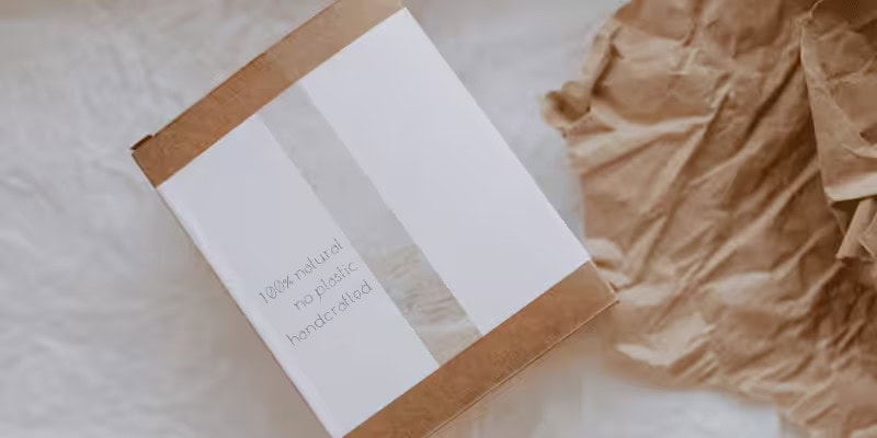 Minimalist kraft paper rigid gift box with eco-friendly label reading "100% natural, no plastic, handcrafted", sustainable packaging design.