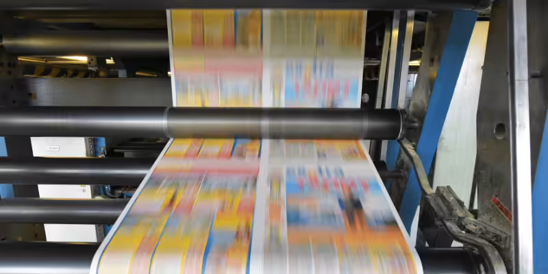Industrial offset printing press running, printing colorful book pages on paper web, ideal for high-volume book printing production.