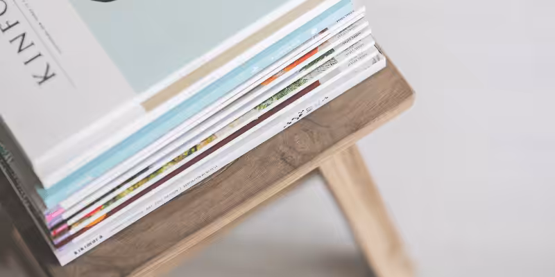 Stack of professionally printed books with diverse covers on a wooden table, showcasing finished book printing results for authors and publishers.