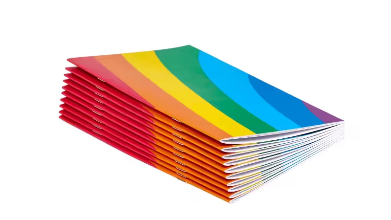 Stack of saddle-stitched booklets with rainbow-striped covers, visible metal staples along the left edge, displayed against a plain white background.