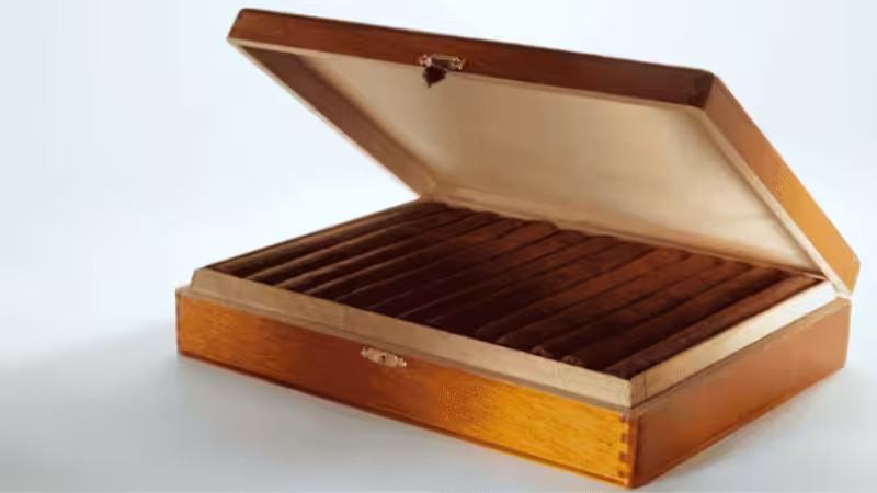 Open polished wooden box for cigars with metal clasps, lined interior, and slots to hold cigars, showcasing premium craftsmanship and storage design.