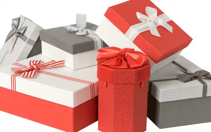 Assortment of uniquely shaped gift boxes in red, white, gray, decorated with satin bows and ribbons.
