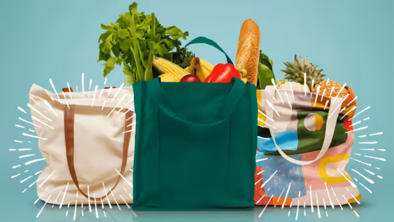 A green shopping bag with vegetables and other groceries