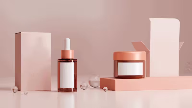 Minimalist pink skincare set: dropper bottle, cream jar, closed box and open box with blank white labels, arranged neatly on a clean surface.