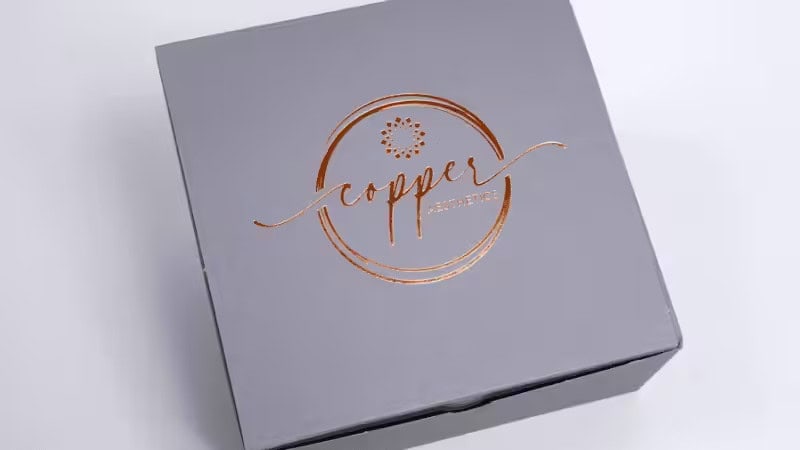 A gray box with a shiny copper-colored logo and text that reads copper and accessories on the lid, placed on a light background.