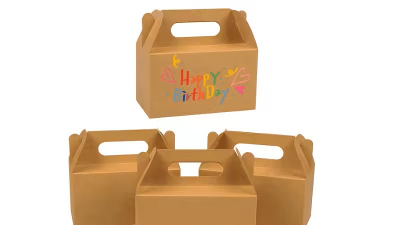 Kraftpapier-Geschenkboxen mit Griffen, eine verziert mit buntem „Happy Birthday“-Schriftzug und Herzen, andere schlicht, die Designs von Kraftpapier-Geschenkboxen mit Griffen präsentieren.