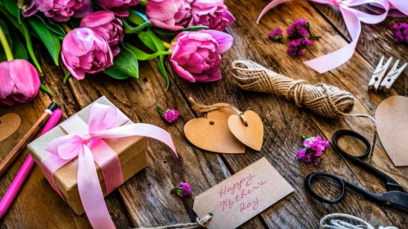 Charming Mother’s Day gift box for women, wrapped in pink ribbon, with fresh tulips and a heartfelt "Happy Mother’s Day" card.