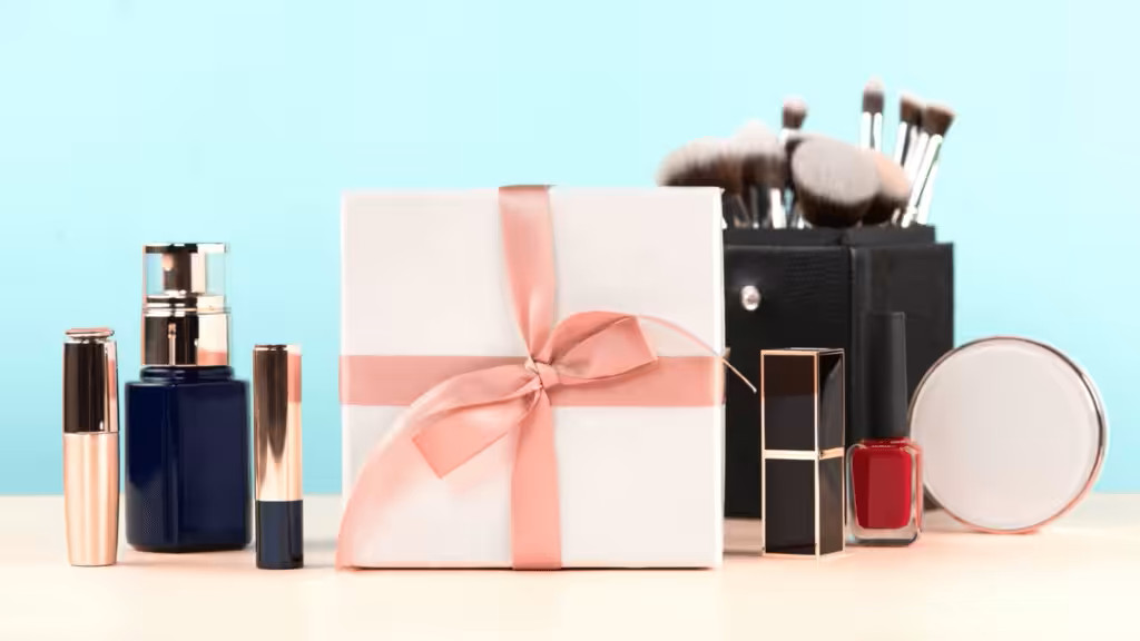 Elegant white gift box for women, surrounded by beauty and make-up essentials like lipsticks, foundation, and makeup brushes.