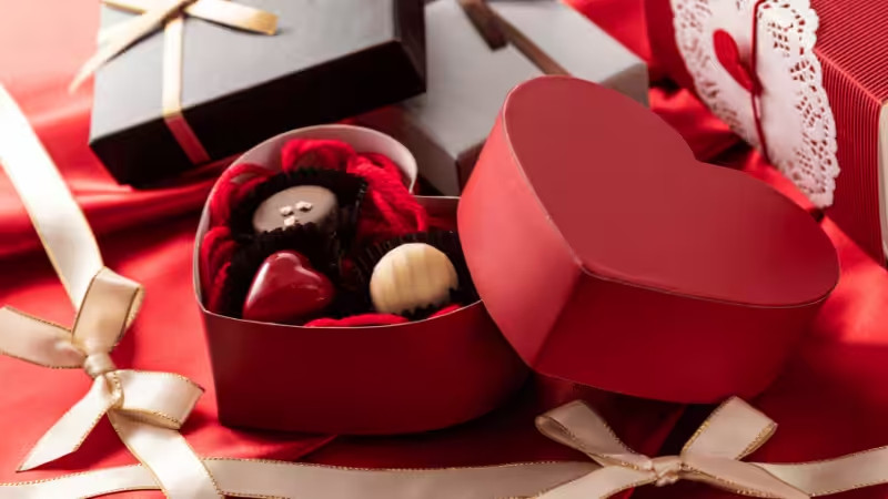 Romantic red heart-shaped themed gift box for women, filled with assorted chocolates and red crinkle paper filler.