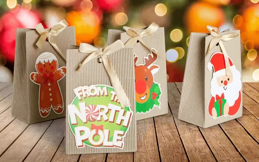 Weihnachtliche Kraftpapier-Geschenktüten mit festlichen Aufklebern (Lebkuchen, Rentier, Weihnachtsmann) und Schleifenverschlüssen, ideal als Weihnachtsgeschenkbox für Kinder.