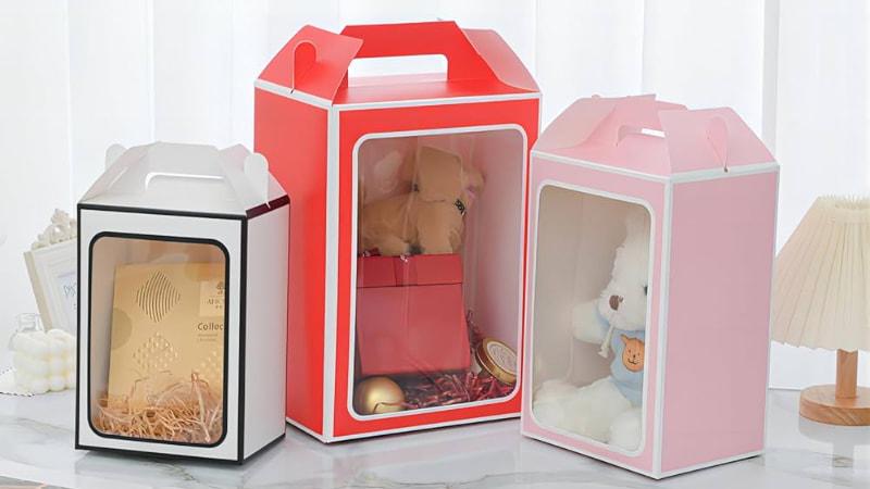 Set of colorful window box packaging with handles, clear windows to display gifts and plush toys inside.
