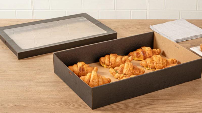 Black window box packaging with clear lid, holding fresh croissants inside, ideal for bakery takeaway.