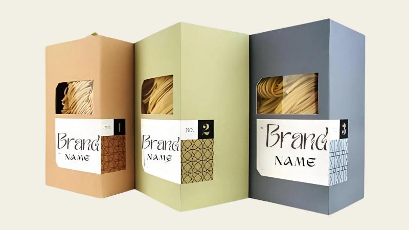Set of three colorful window box packaging mockups with clear windows, brand name labels, and decorative patterns.