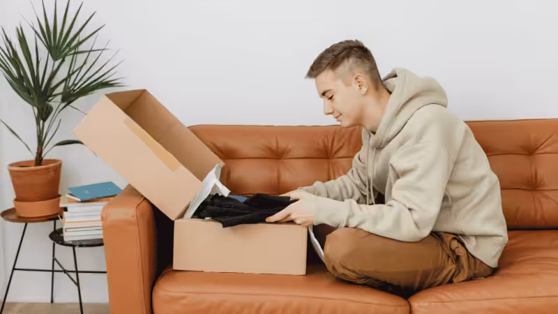 a manis opening a box with some clothes