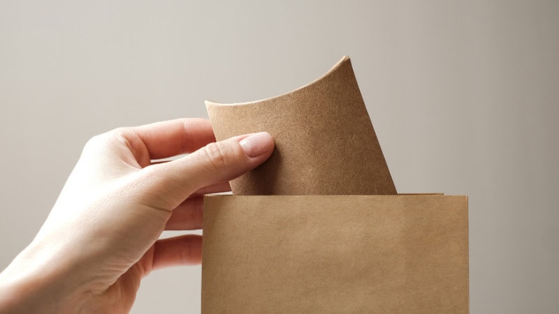 someone is taking a kraft pillow box from a paper bag