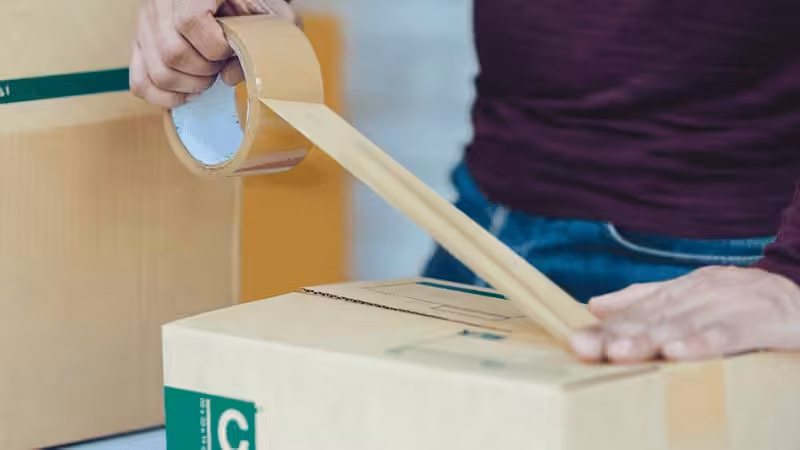 A man using tape to seal a package