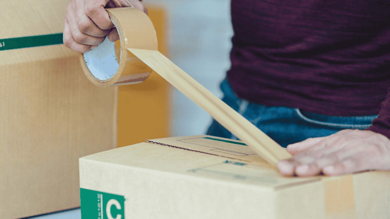 A man using tape to seal a package