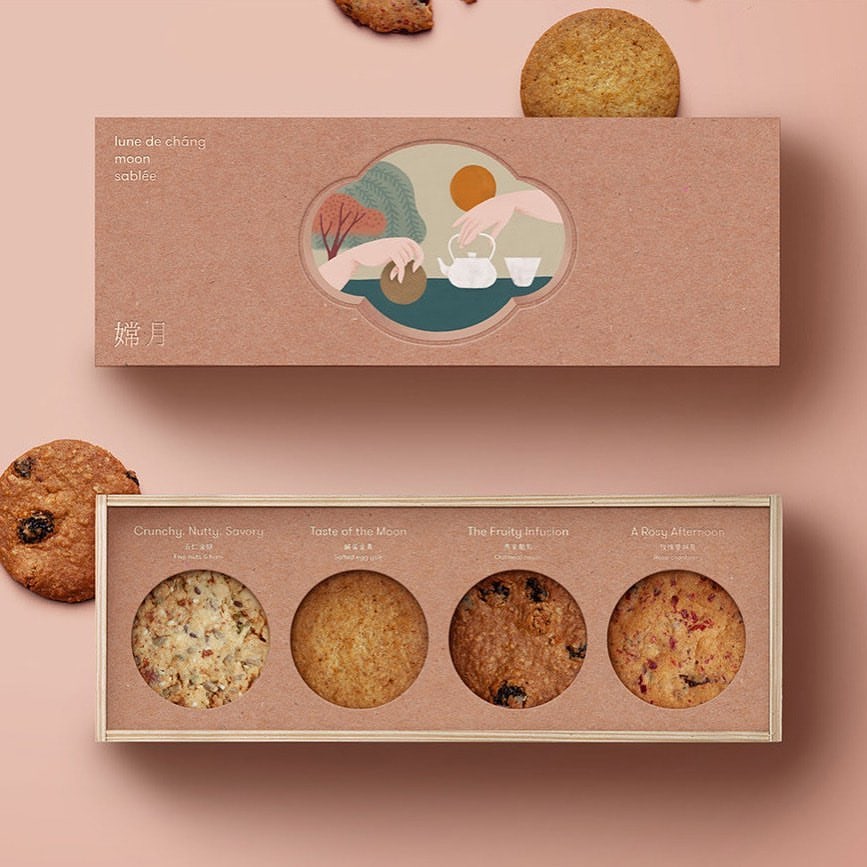 Caja de panadería personalizada, rectangular y alargada, con ventana recortada e ilustración de un paisaje chino, que contiene cuatro galletas de sabores variados.